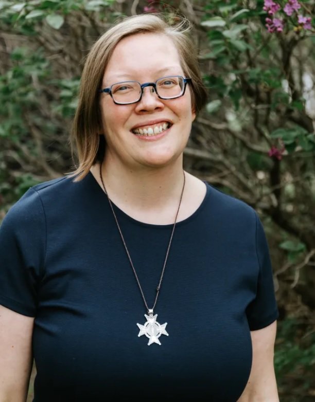 Sister Julia Walsh is standing in front of a flowering shrub