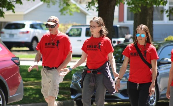 three people, with Sister Kristin Peters in middle, walking wearing their red MMIW 5K tshirts