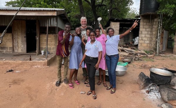 six african americans gathered around a white man on a dirt road in front of houses in a village  