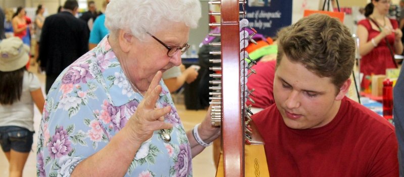 Sister Malinda Gerke teaching a young man how to play the harp