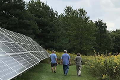 three people walking next to a row of solar panels