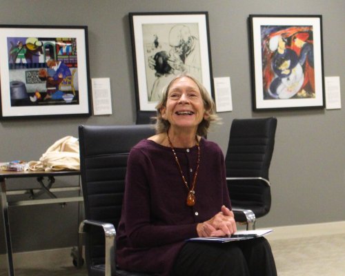 woman-sitting-in-black-chair-wearing-wine-colored-sweater-in-front-of-framed-art