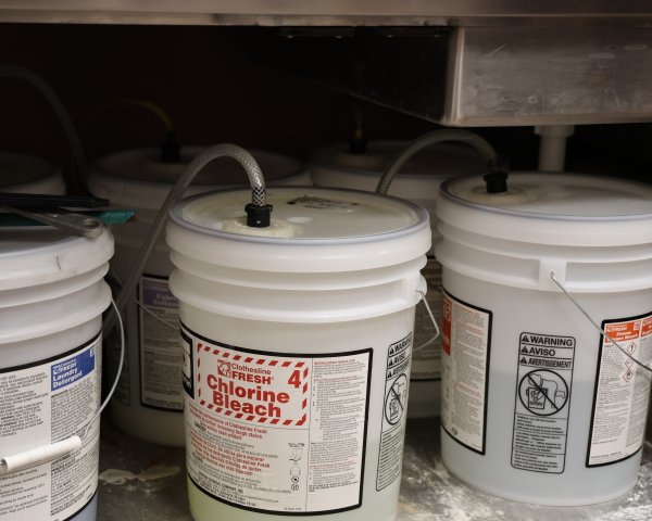 three-white-five-gallon-buckets-connected-to-hoses-under-sink