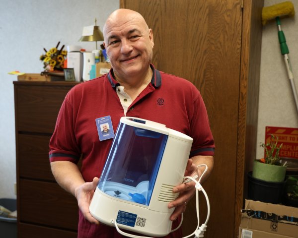 bald-man-in-red-and-blue-polo-shirt-holding-blue-and-white-humidifier