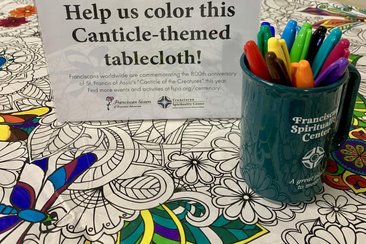 cup of colorful markers sitting on a patterned tablecloth